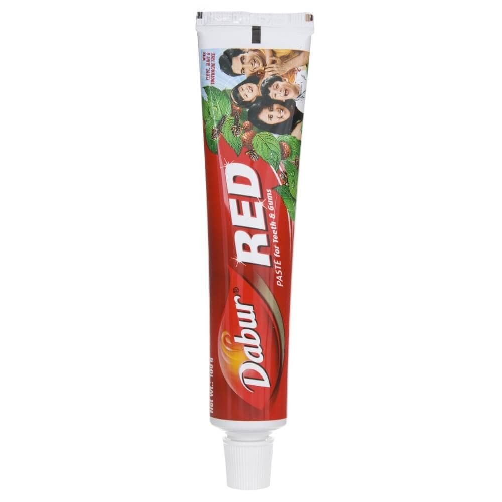 Tube de dentifrice Dabur Red avec un design rouge et une image de famille sur le devant.