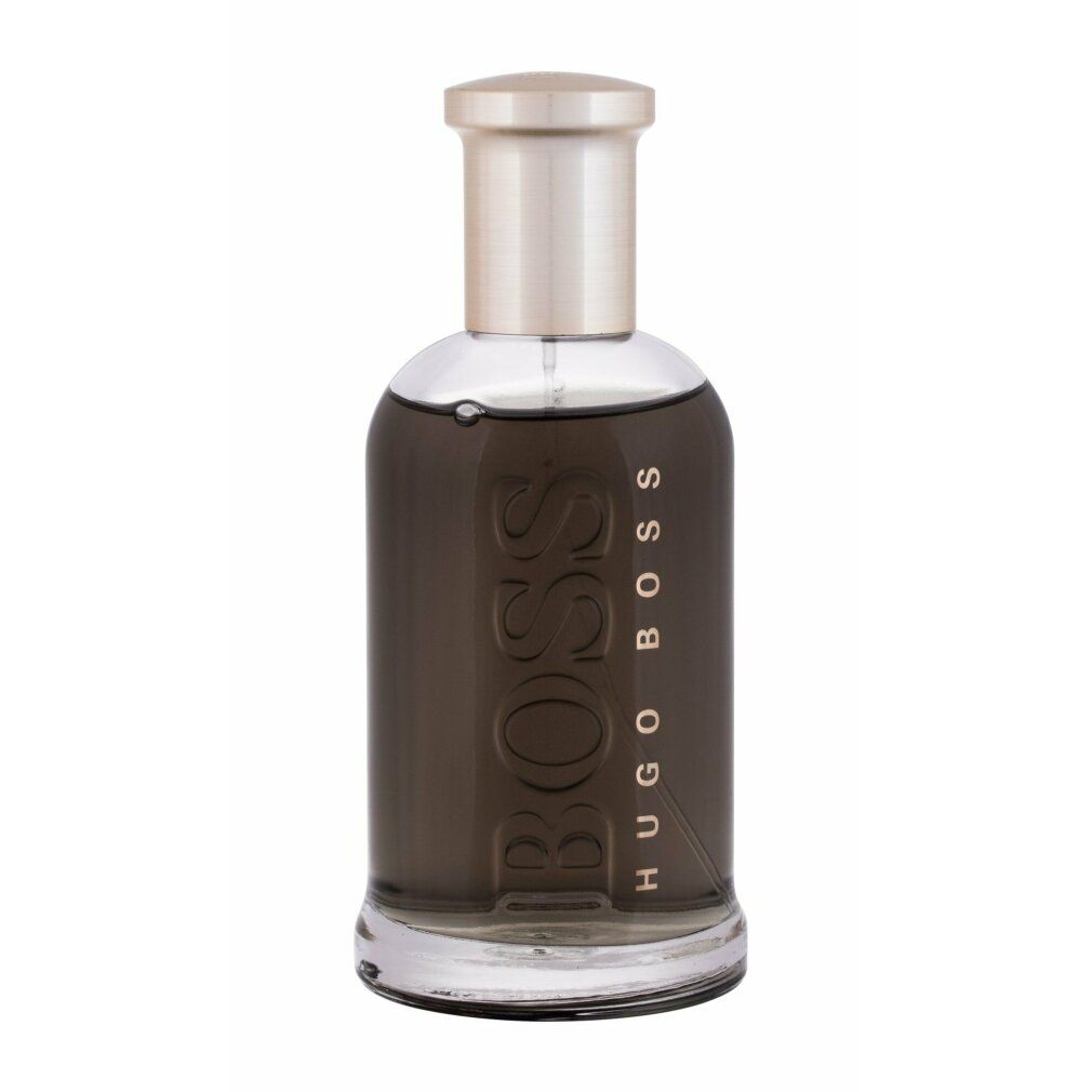 Parfumfles met gouden dop. Opschrift BOSS HUGO BOSS. Glazen fles met licht donkere vloeistof.