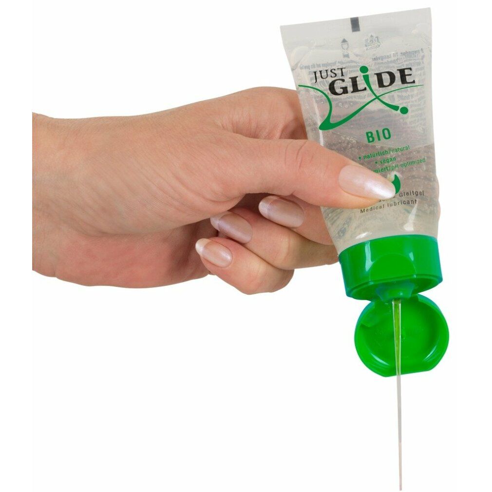 Hand houdt tube vast. Gel komt uit opening. Groene dop. Product: Just Glide Bio. Transparante gel.