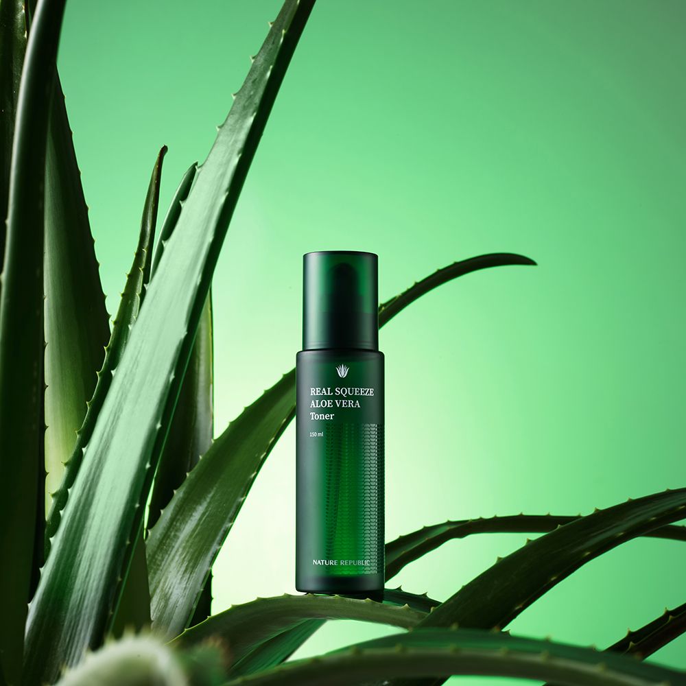 Flacon vert de toner à l'aloe vera, entouré de feuilles d'aloe vera sur fond vert.