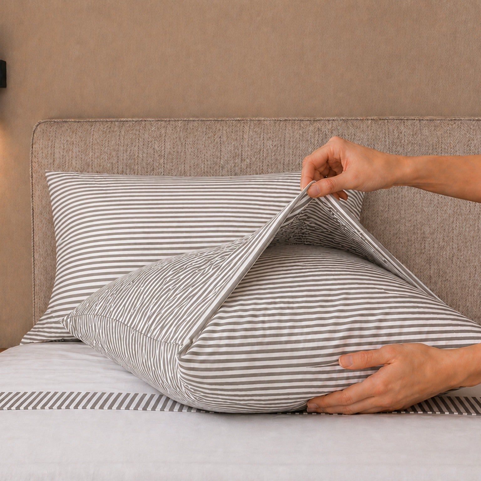 Een opgemaakt bed met gestreept beddengoed en een nachtkastje.