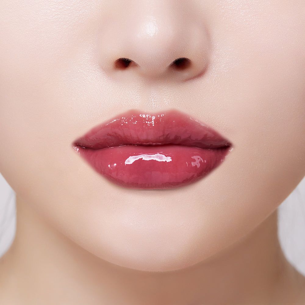 Glanzende, bessenkleurige lipgloss op volle lippen.