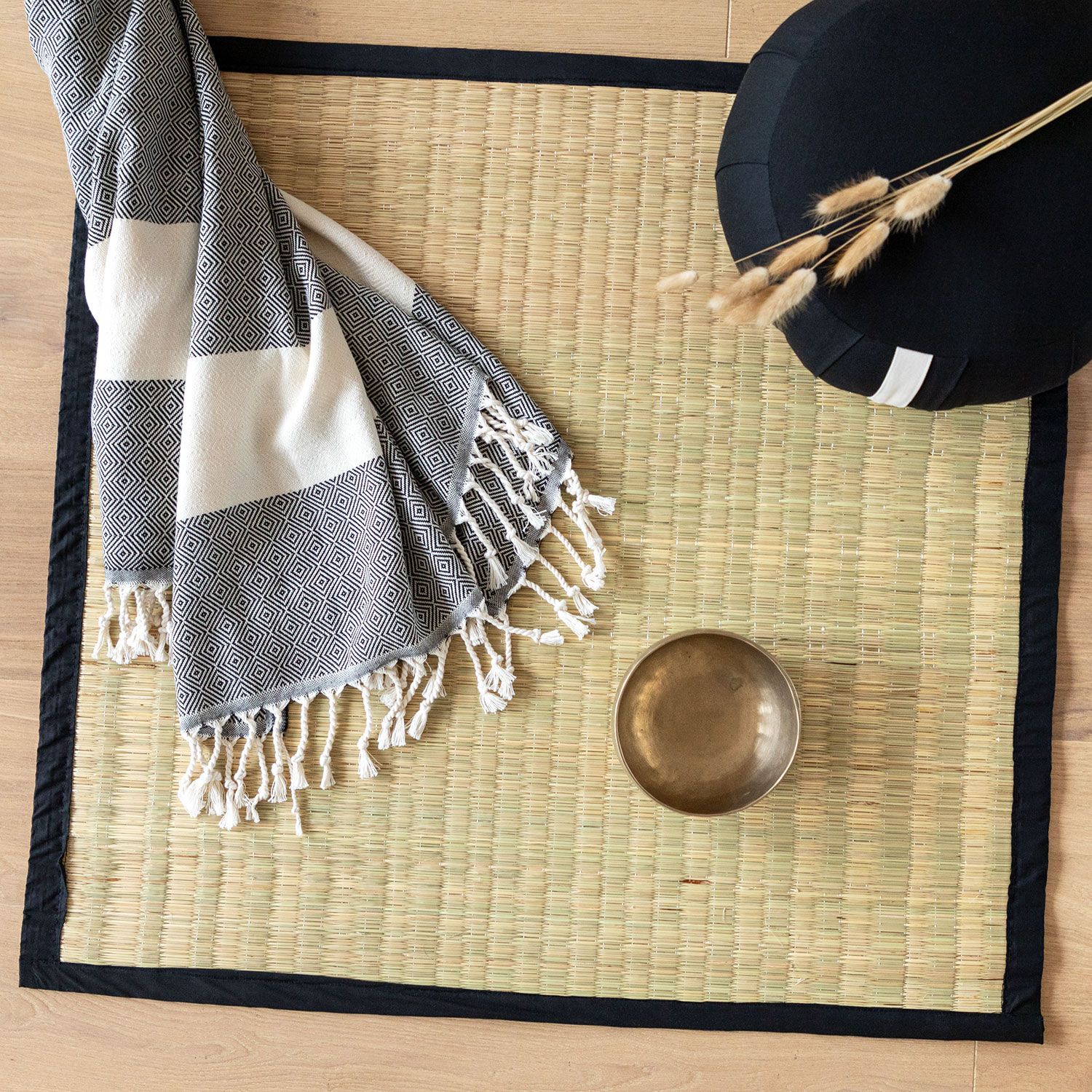 Tatami-mat met zwarte rand, met daarop een deken, een kom en een kussen.