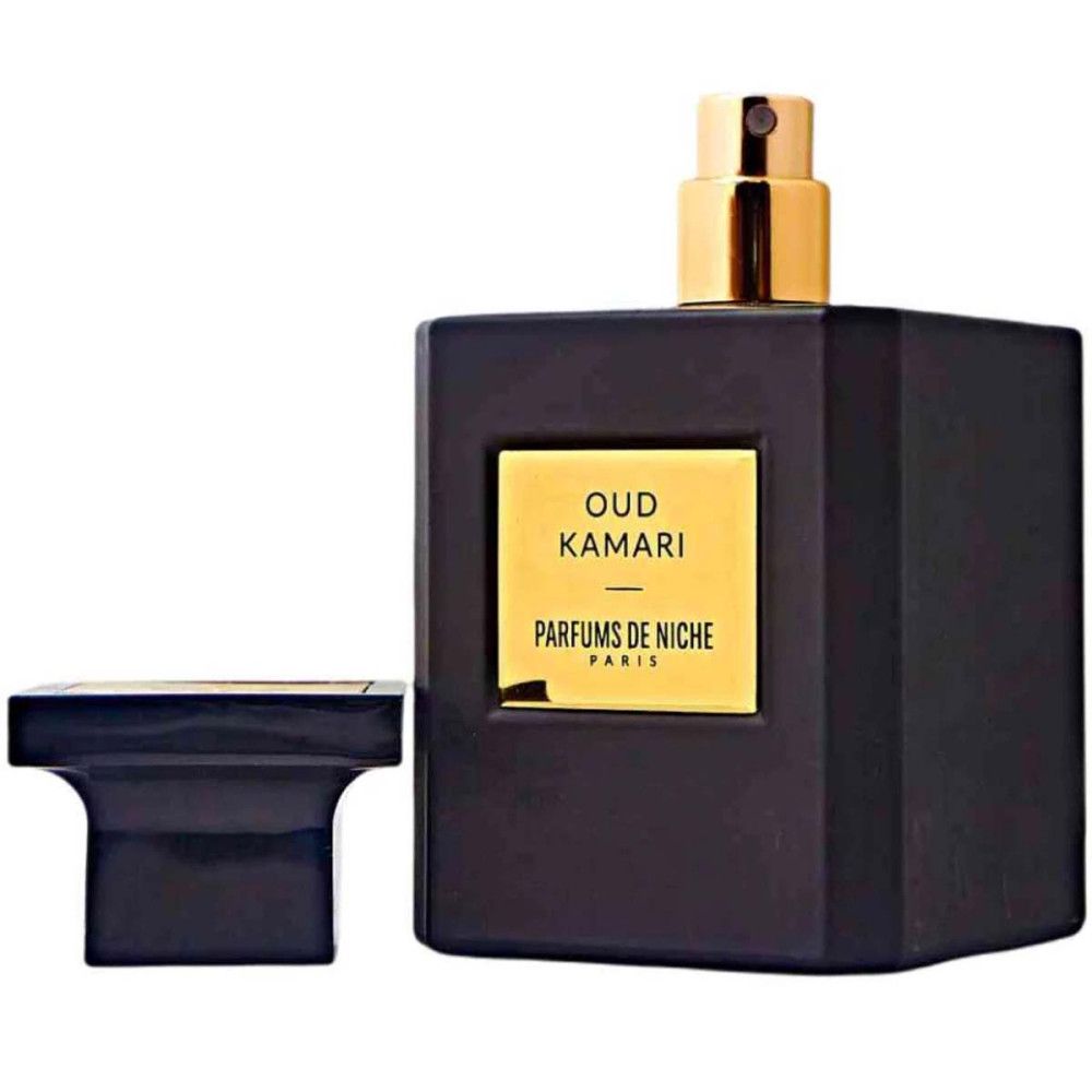 Zwarte fles met gouden dop. Label met "Oud Kamari" en "Parfums de Niche". Dop ernaast.