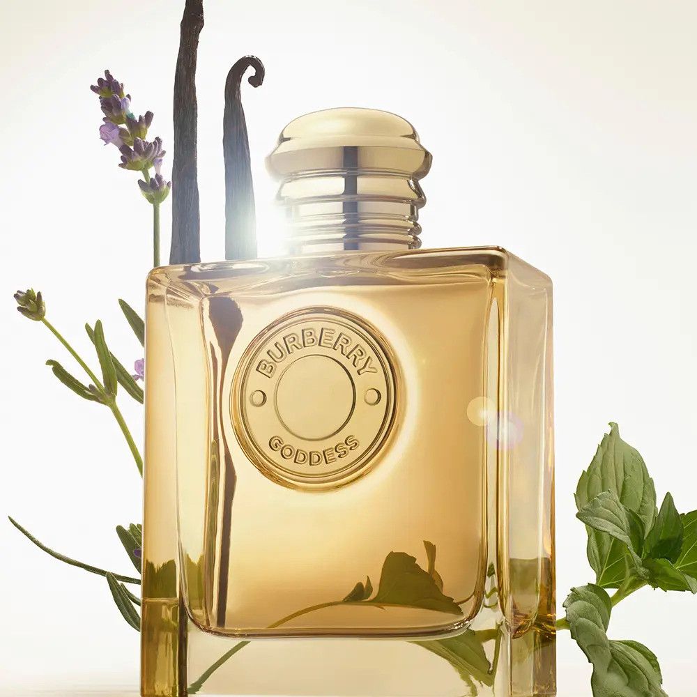 Flacon doré avec bouchon doré. Entouré de lavande, vanille et menthe. Lumière de fond vive.