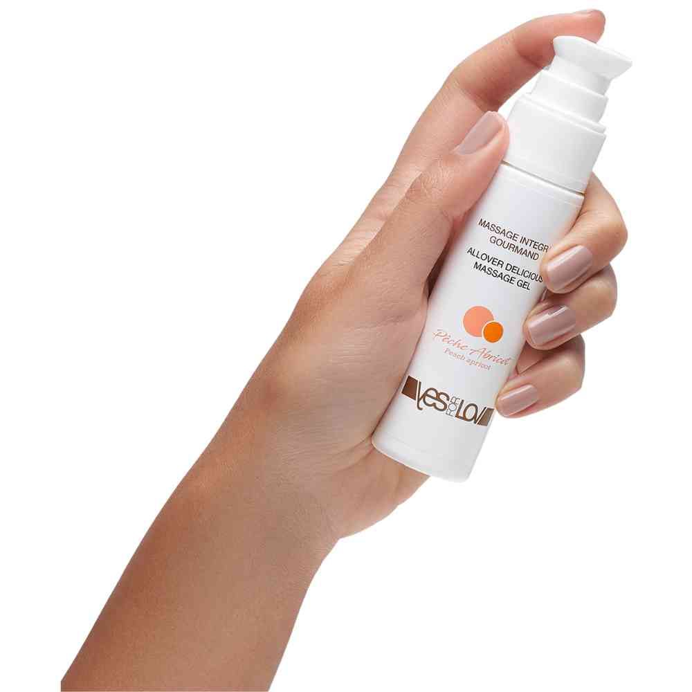 Een hand houdt een fles YESforLOV Allover Delicious Massage Gel met pompdispenser vast.