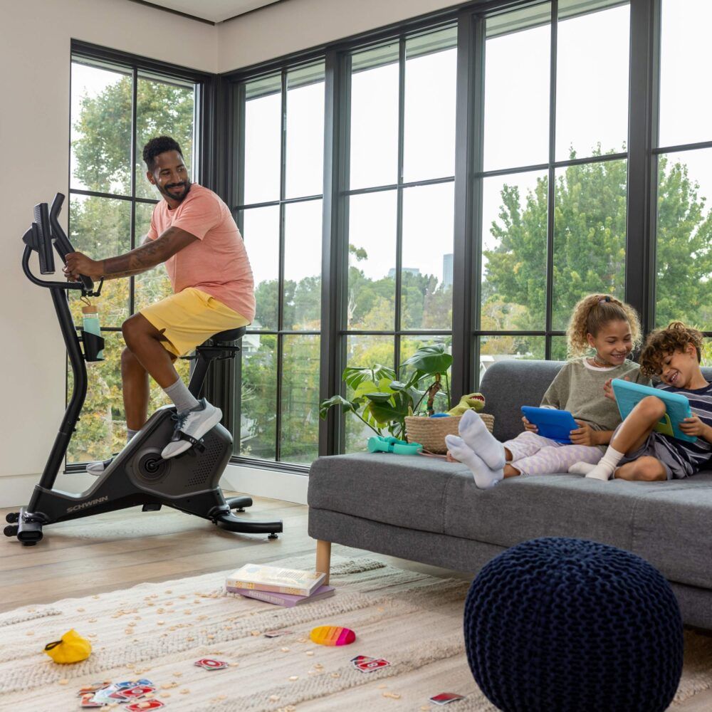 Homme faisant de l'exercice sur un vélo d'appartement. Enfants jouant. Schwinn Fitness 590U.