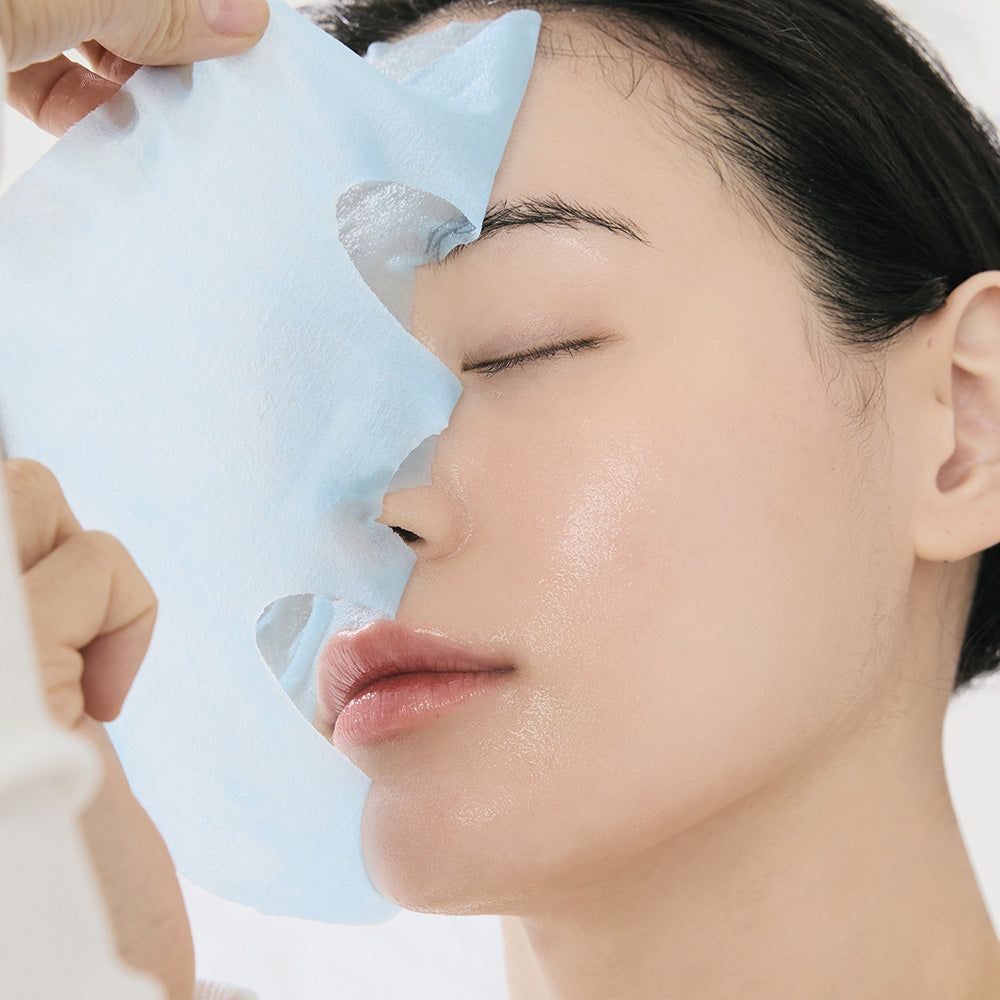 Gros plan d'un visage avec un masque facial en cours d'application. Le masque est bleu et recouvre la peau.