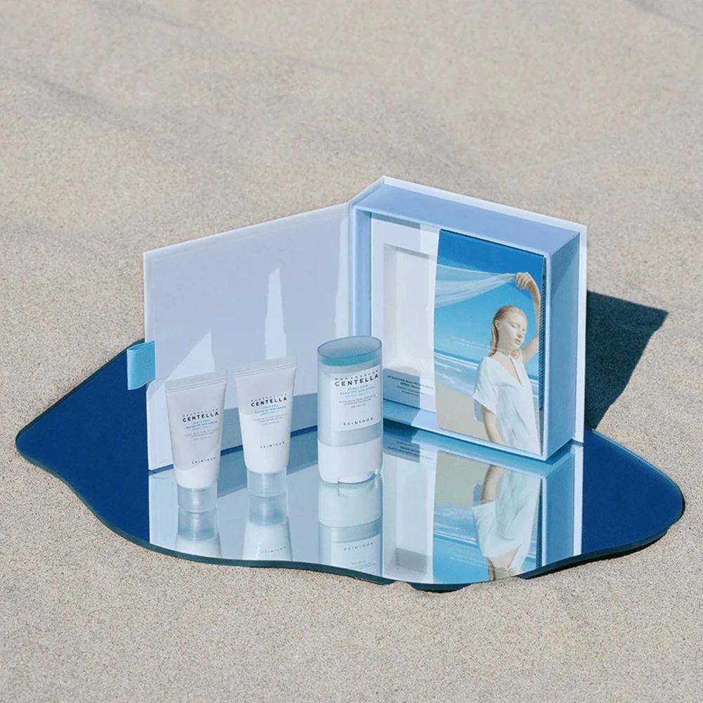 Productset op spiegel. Bevat zonnestick en serums. Weerspiegeling van de set en een vrouw op het strand.
