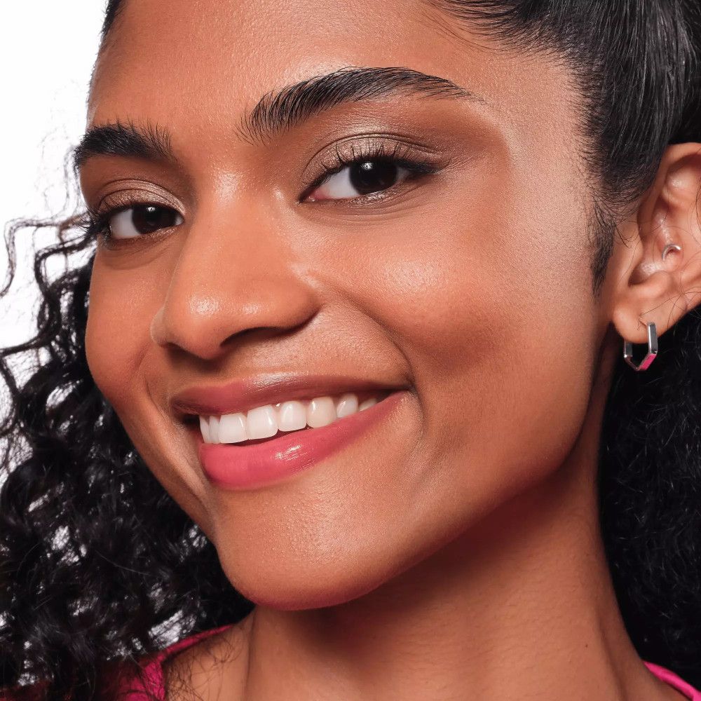 Gros plan d'une femme avec du fard à paupières crème brun sur les paupières. Elle sourit.