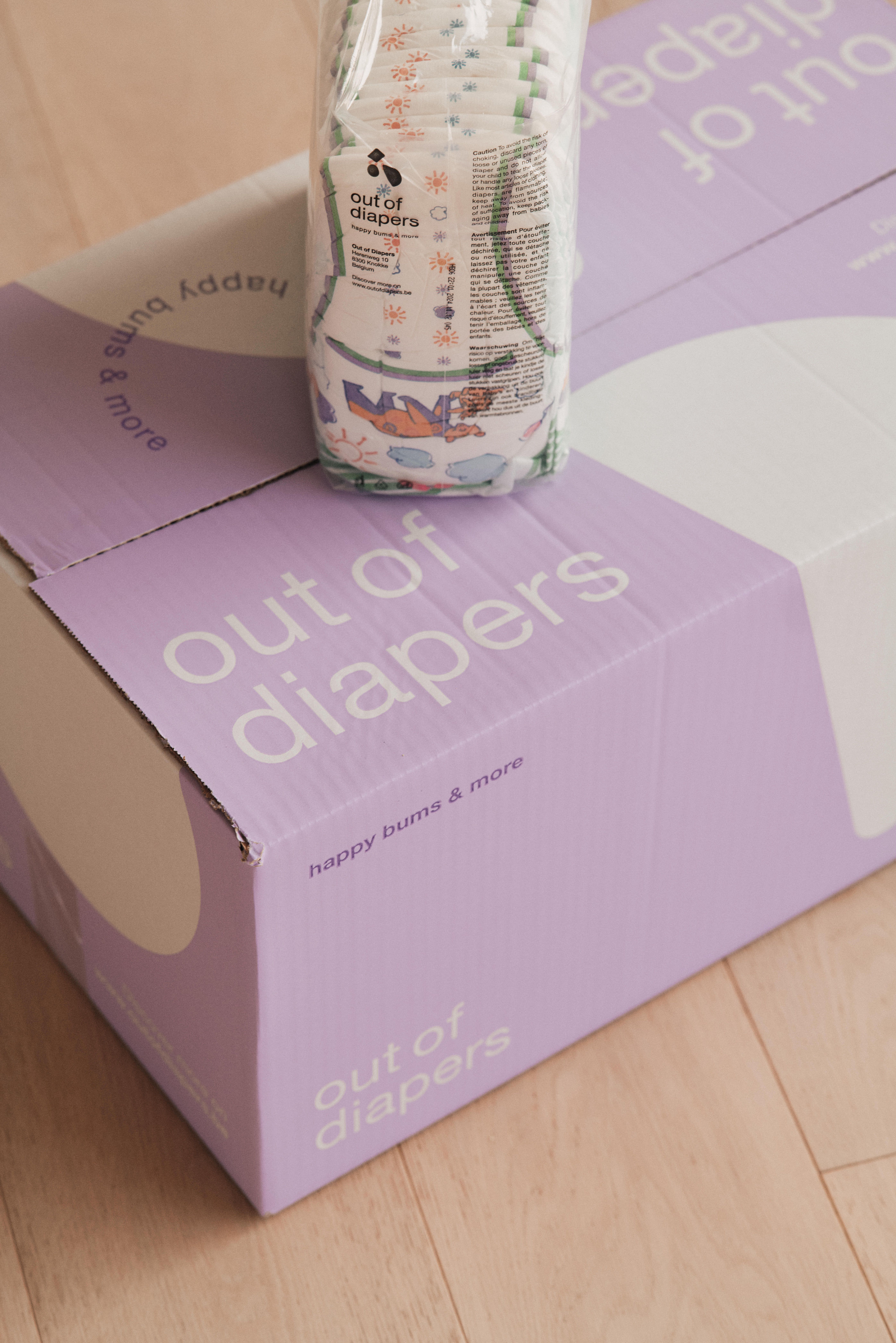 Kartonnen doos met 'out of diapers'. Een pak luiers ligt erop.