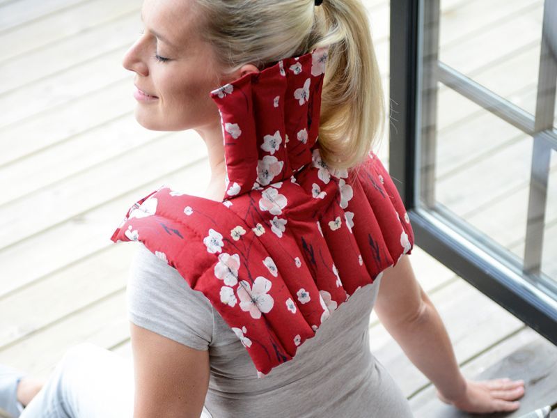 Personne avec compresse rouge à motif floral sur la nuque. Femme assise près d'une fenêtre.