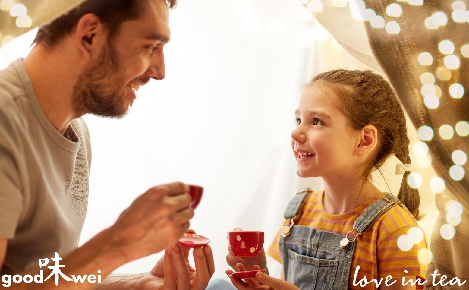 Man en meisje drinken thee uit rode kopjes. Logo "goodwei" linksonder. Tekst "love in tea" rechts.