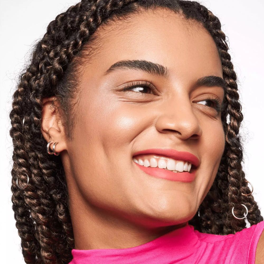 Vrouw met gevlochten haar en roze lippenstift. Draagt oorbellen.