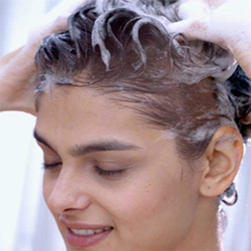 Close-up van een vrouw die haar haar wast. Schuim op het haar. Ogen gesloten.
