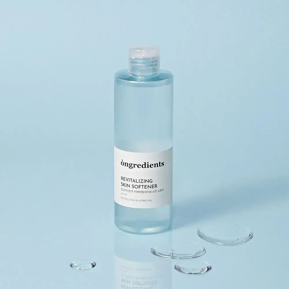 Transparante fles met wit etiket en waterdruppels. Opschrift: Ongredients, Revitalizing Skin Softener. Heldere vloeistof.