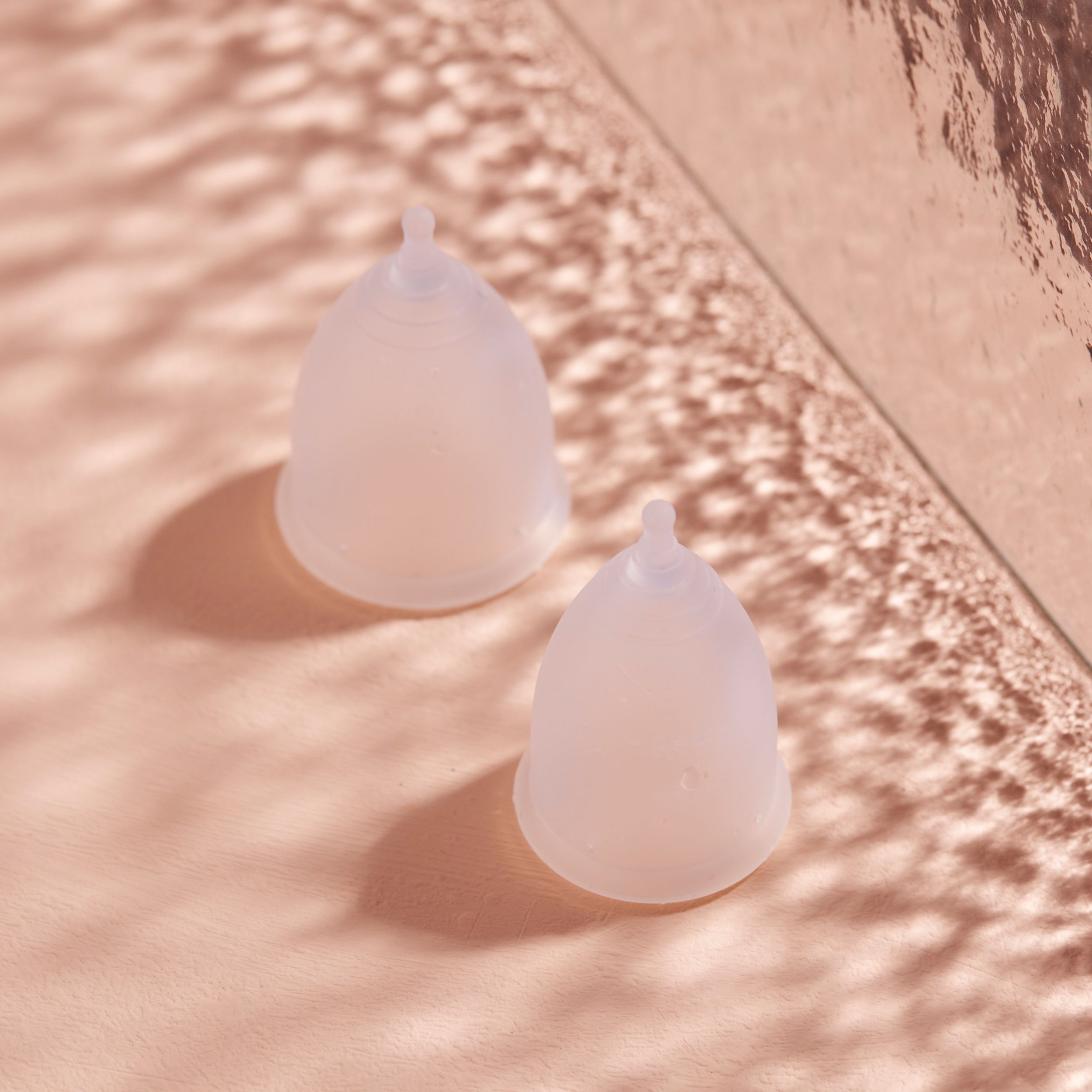 Deux coupes menstruelles translucides en silicone médical sur fond clair.