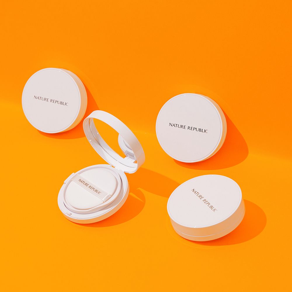 Meerdere witte, ronde houders op oranje achtergrond. Sommige open, met sponzen en spiegels. Merknaam zichtbaar.