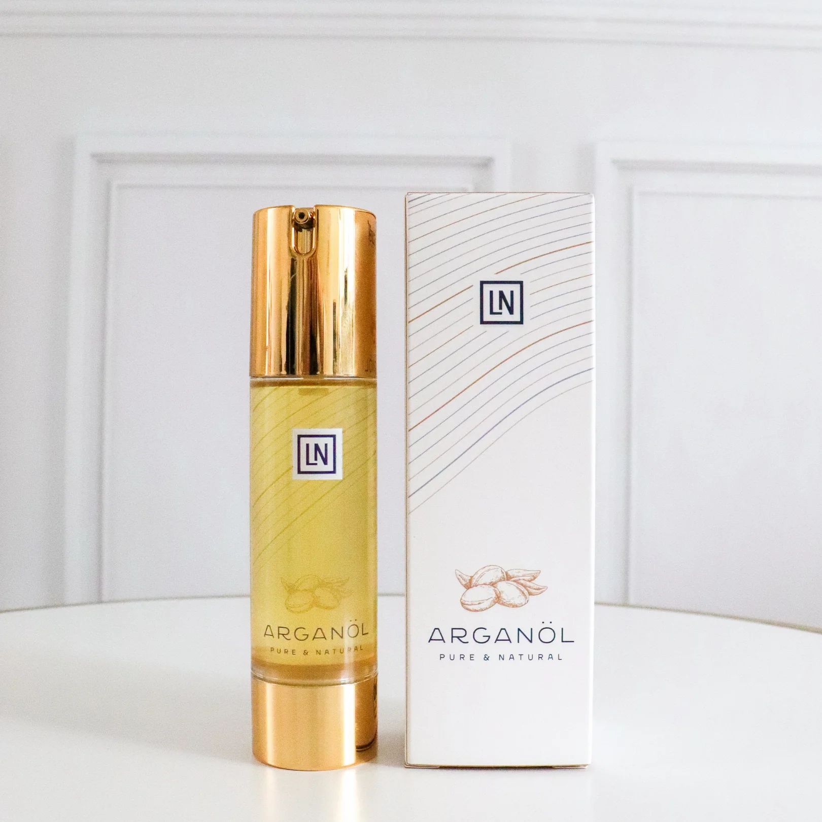 Arganolie fles en verpakking naast elkaar. Fles met gouden dop. Verpakking wit met logo LN.