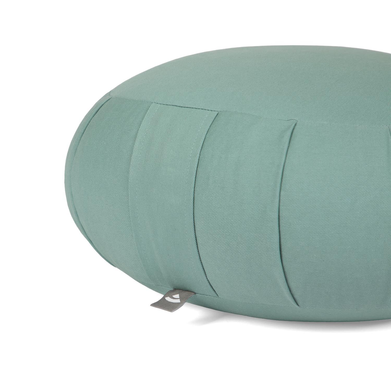 Gros plan sur coussin de méditation vert menthe. Plis et petite étiquette.