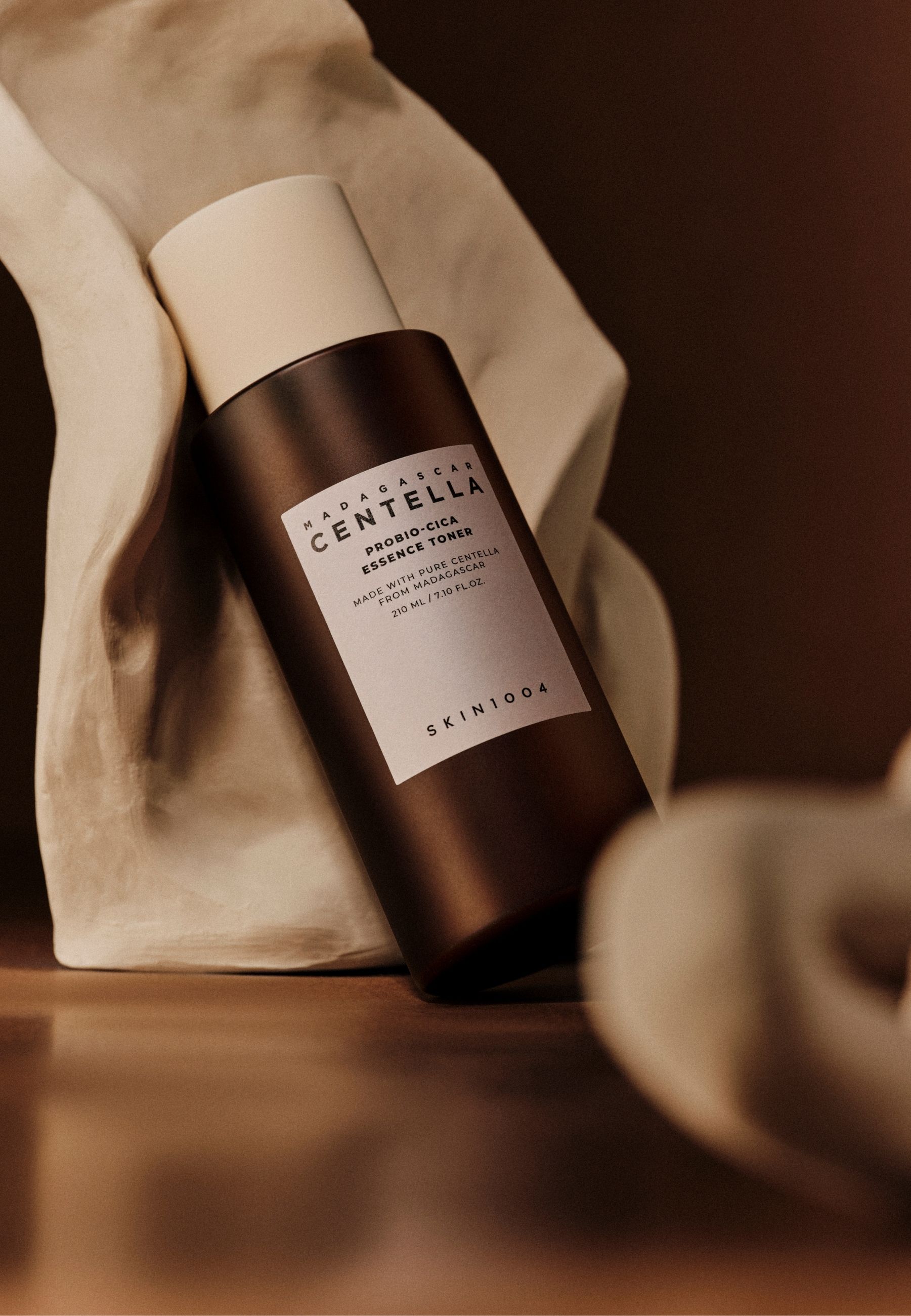 Bruine fles met witte dop, voor witte stof. Tekst: MADAGASCAR CENTELLA, PROBIO-CICA Essence Toner, SKIN1004.