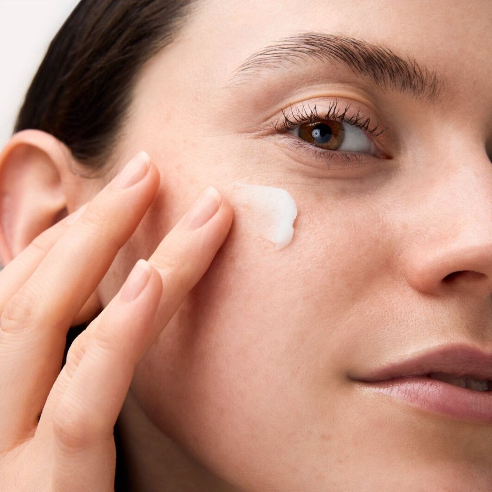 Gros plan d'une femme appliquant de la crème sur son visage. Peau claire, doigts touchant la peau.