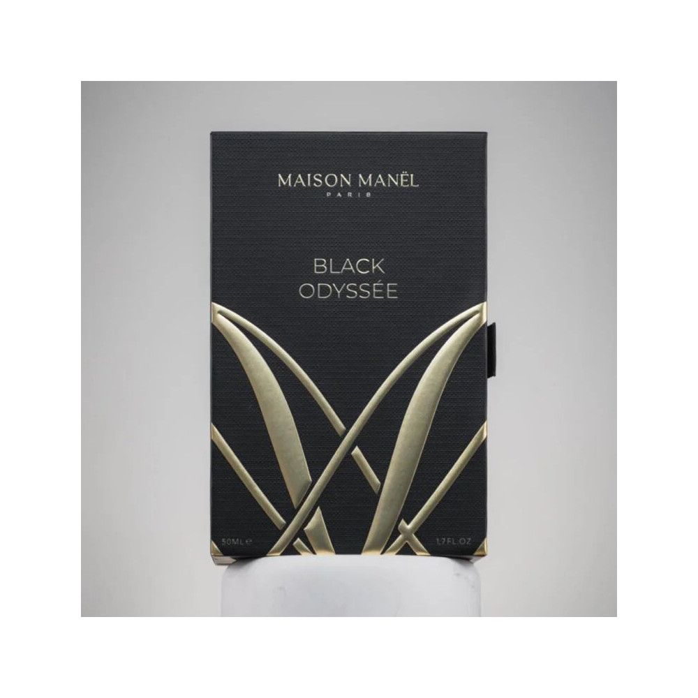 Zwarte rechthoekige doos met gouden tekst. Opschrift: Maison Manel Paris, Black Odyssée. Zwarte sluiting.
