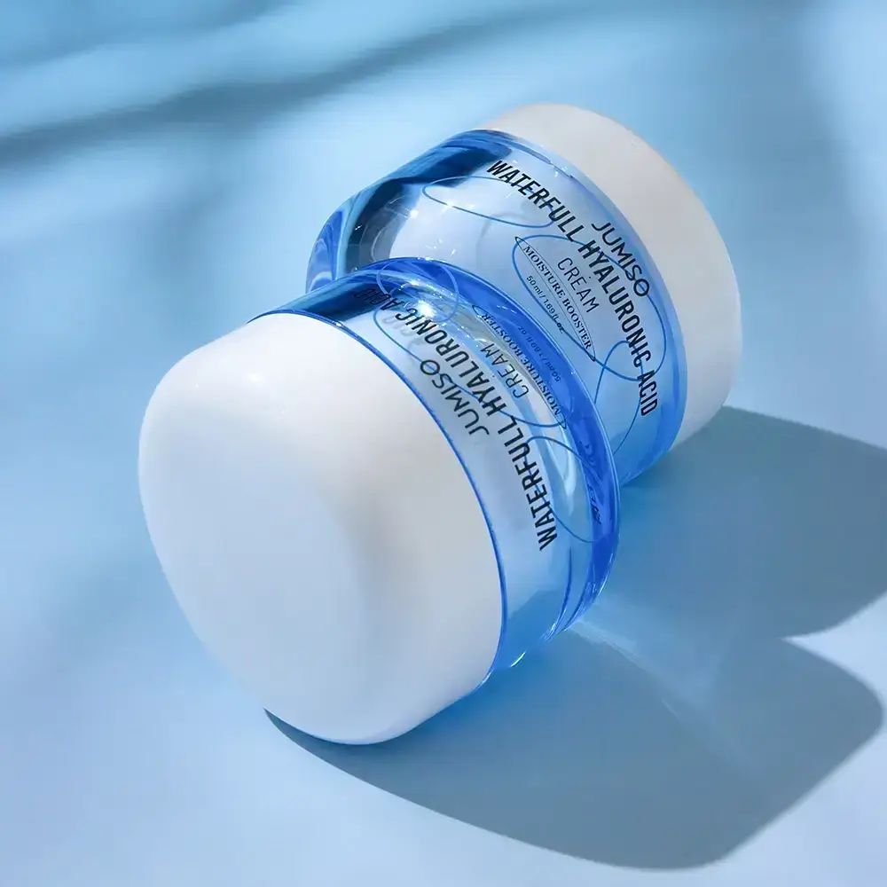 Deux pots de crème. Inscription: JUMISO WATERFULL HYALURONIC ACID CREAM. Crème pour peau sèche. Emballage bleu et blanc.