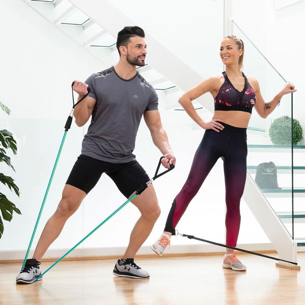 Twee personen trainen met weerstandsbanden. Handvatten en banden in verschillende kleuren. Sportkleding. Lichte omgeving.