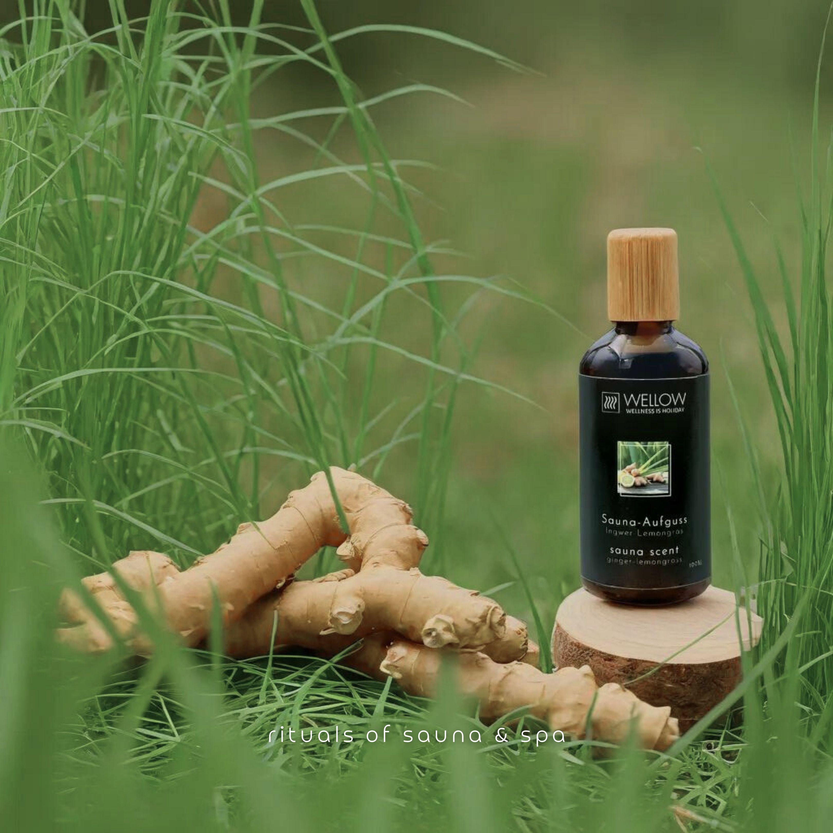 Bruine glazen fles met houten dop op een stuk hout, omringd door gember en gras. Tekst: rituals of sauna & spa.