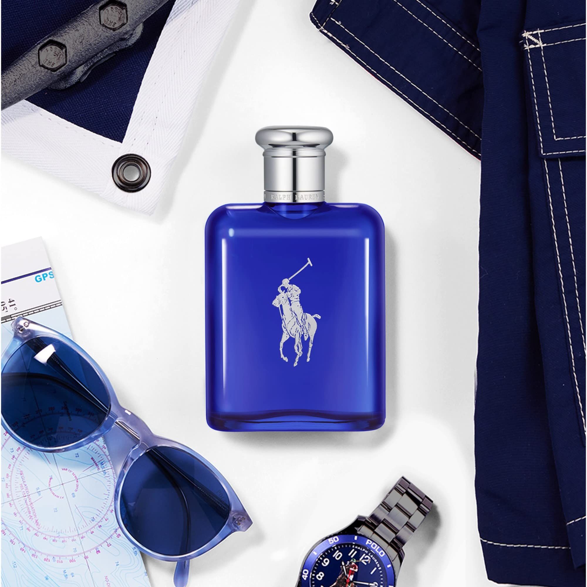 Flacon de parfum bleu avec bouchon argenté, entouré d'accessoires : lunettes de soleil, montre, carte et tissu.