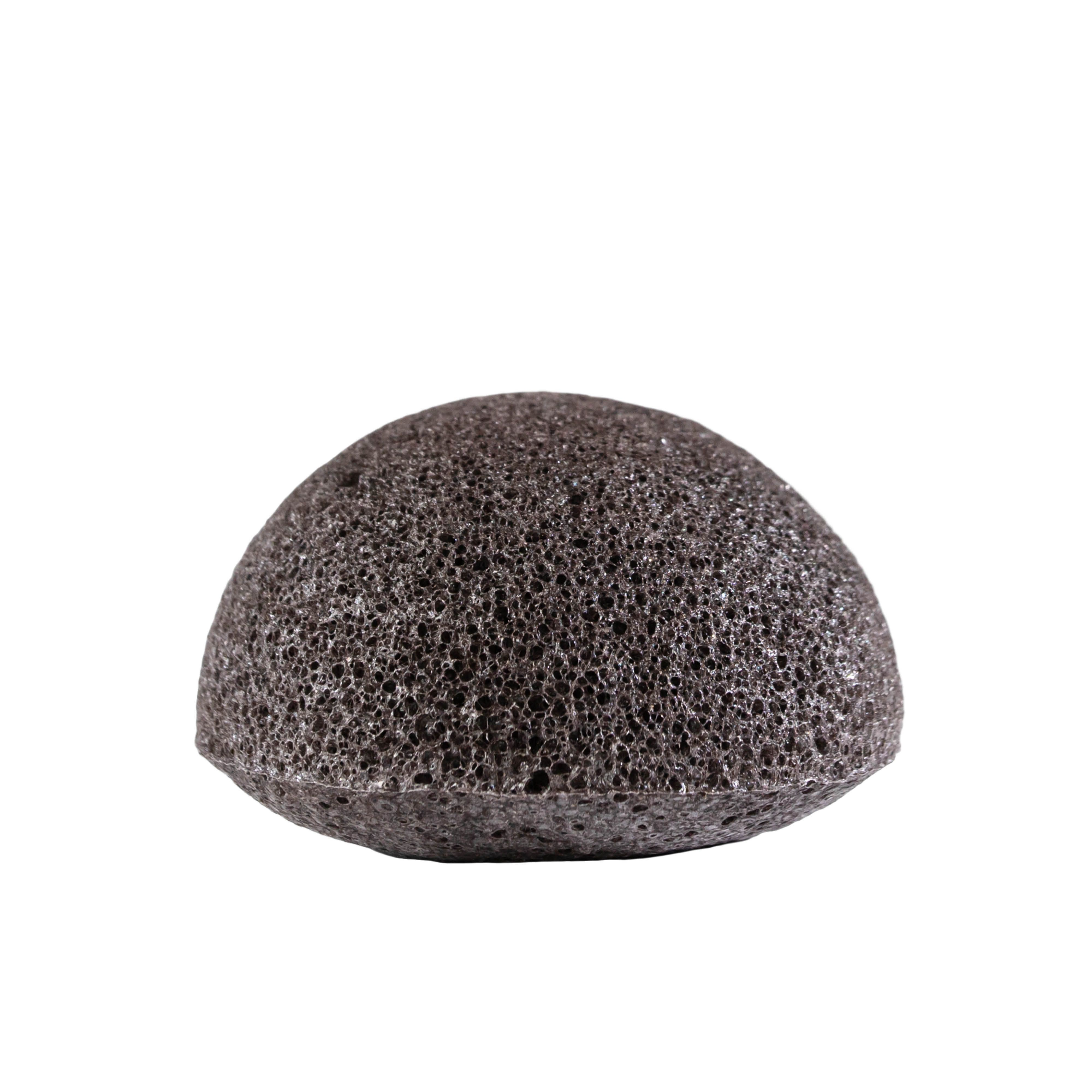 Éponge Konjac, gris foncé, hémisphérique. Structure poreuse visible.