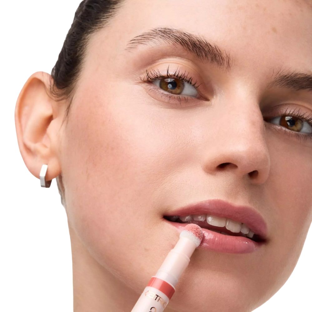 Vrouw brengt lipolie aan met applicator. Roze lipolie.