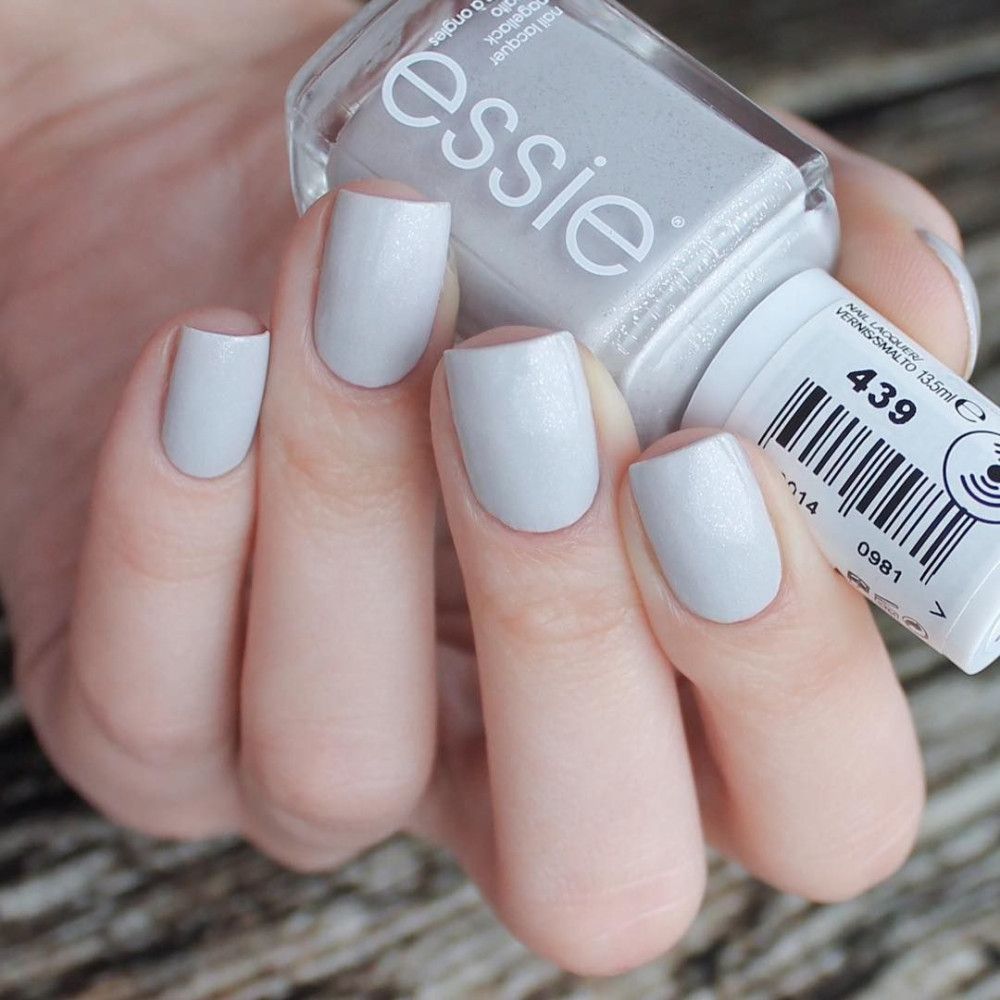 Essie nagellak. Fles en gelakte nagels in lichtgrijs. Opschrift 'essie'.