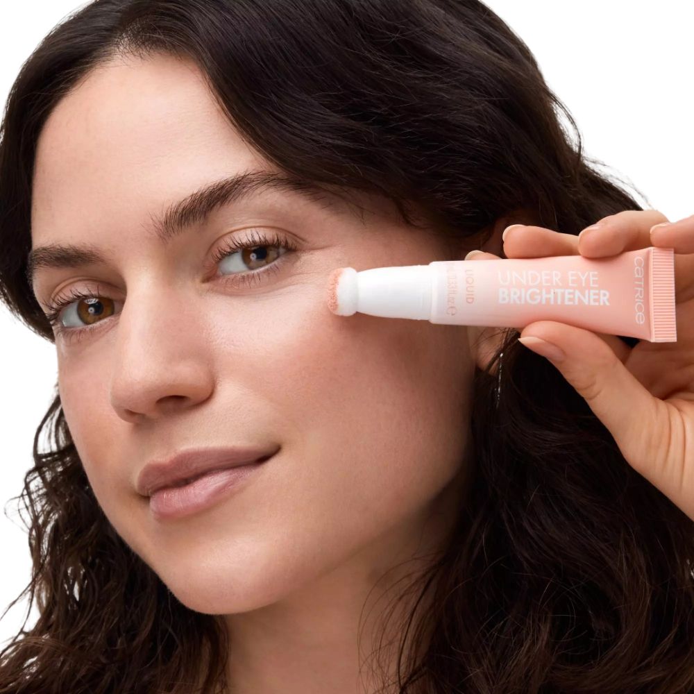 Femme tenant un tube avec applicateur. Inscription: UNDER EYE BRIGHTENER.