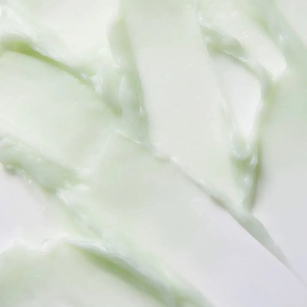 Gros plan sur un baume nettoyant blanc-vert. Texture avec des stries lisses et irrégulières.