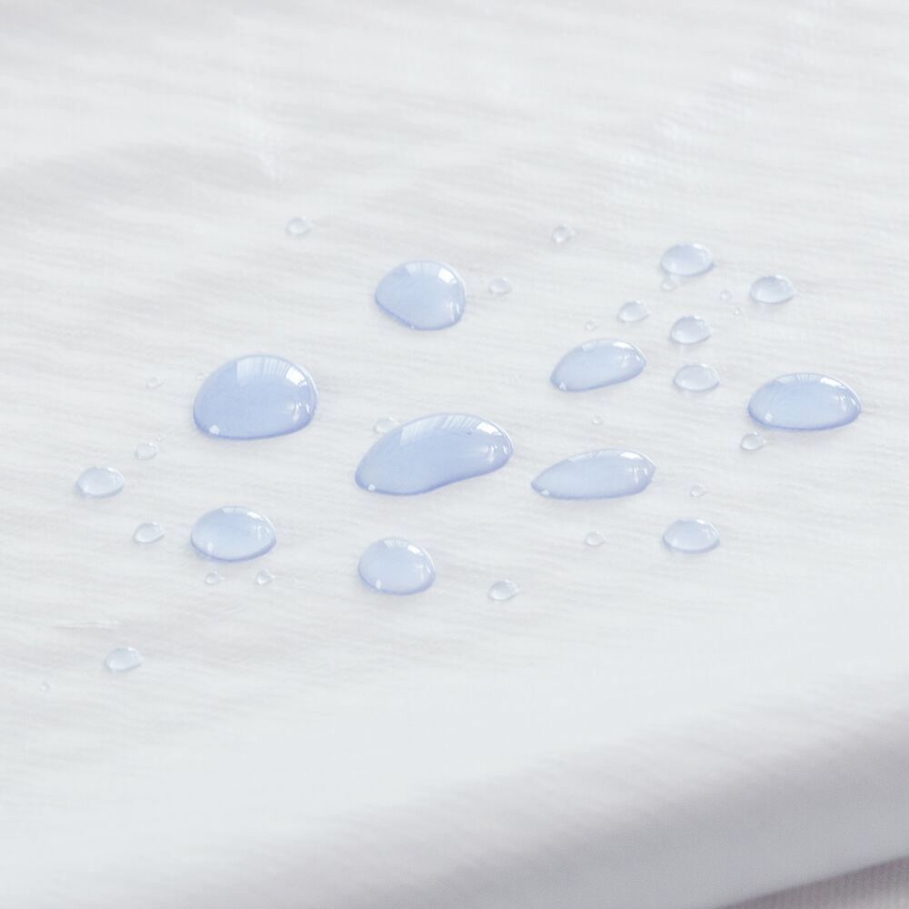 Wit textiel met waterdruppels. De druppels zijn rond en liggen op het oppervlak.
