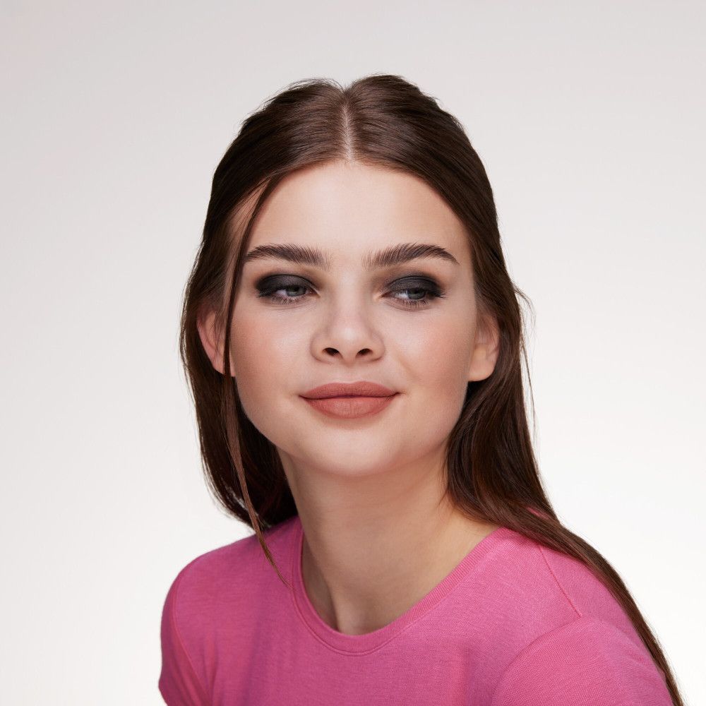 Portret van een vrouw met oogschaduw. Ze draagt een roze top.