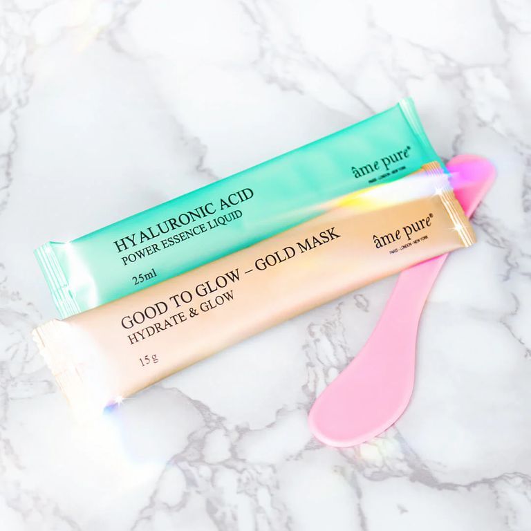 Deux sachets de masques et une spatule. Vert et or. Texte : âme pure, Hyaluronic Acid, Good to Glow. Sur marbre blanc.