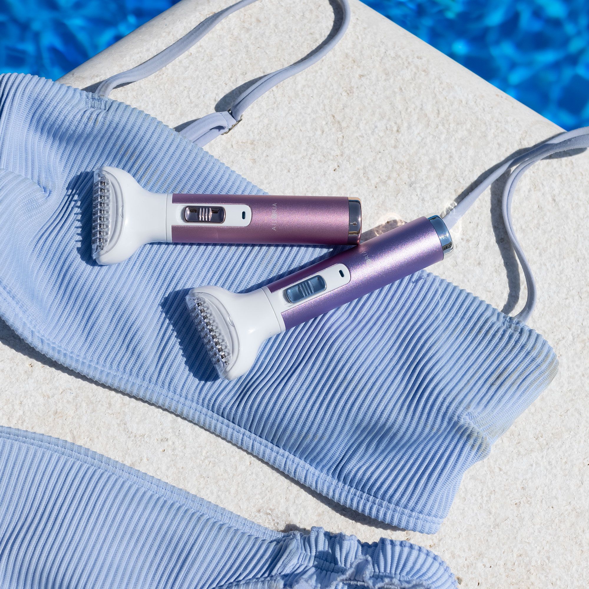 Deux rasoirs corporels sur un bikini bleu clair. Violet et rose.