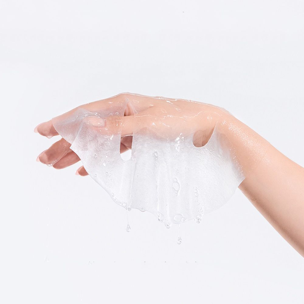 Transparant gezichtsmasker in een hand. Vloeistof druppelt van het masker. Achtergrond: wit.