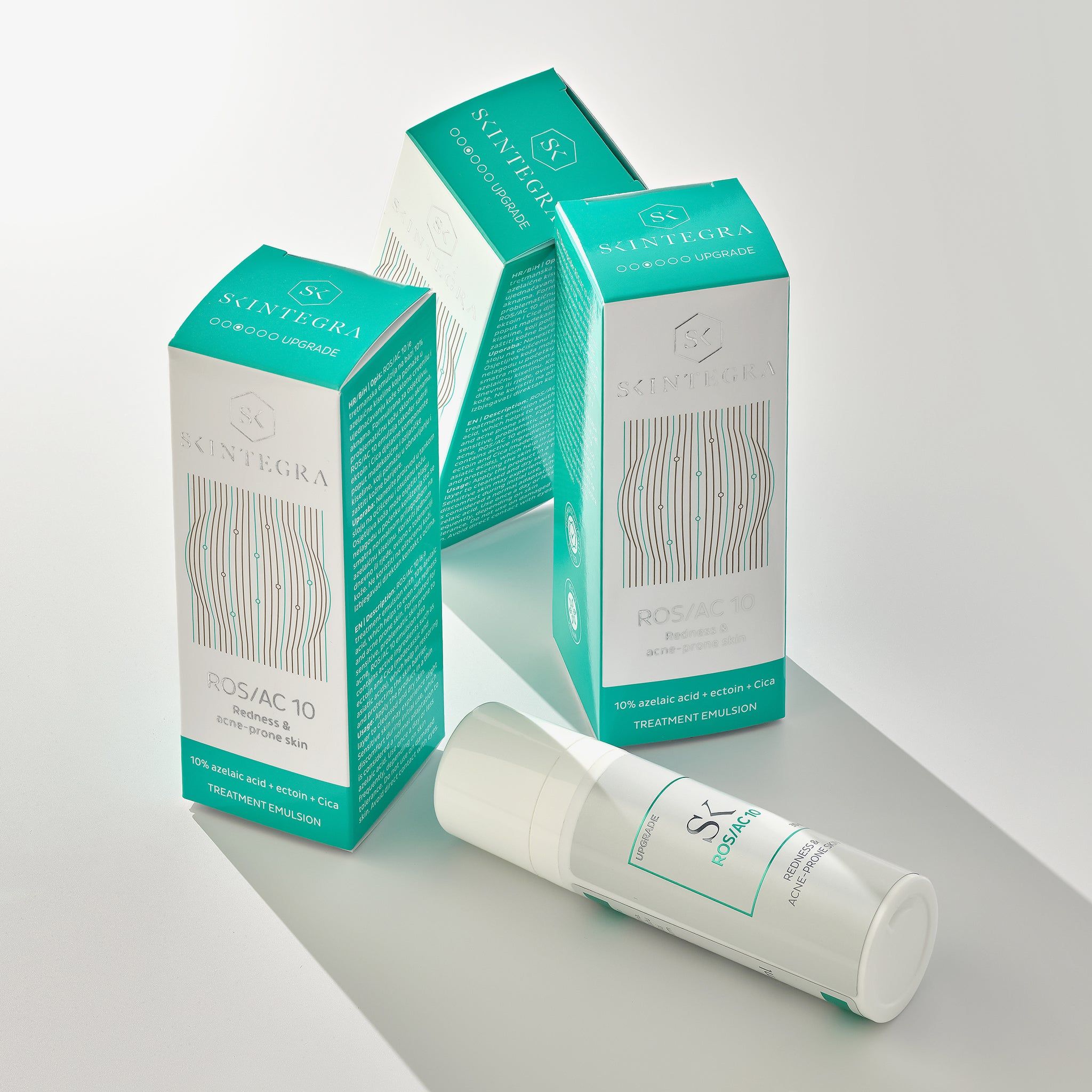 Trois emballages et un flacon. Inscription : Skintegra, ROS/AC 10, Redness & acne-prone skin. Texte : 10% azelaic acid.