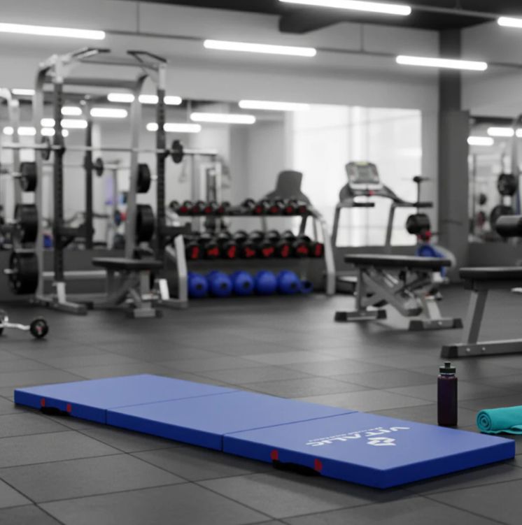 Tapis de yoga bleu dans une salle de sport. Logo VITALIC. Équipement de fitness en arrière-plan. Serviette et bouteille.