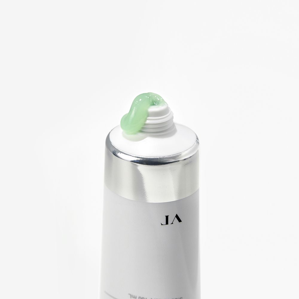 Gros plan d'un tube. Tube blanc avec bouchon argenté, crème verte sortant de l'ouverture.