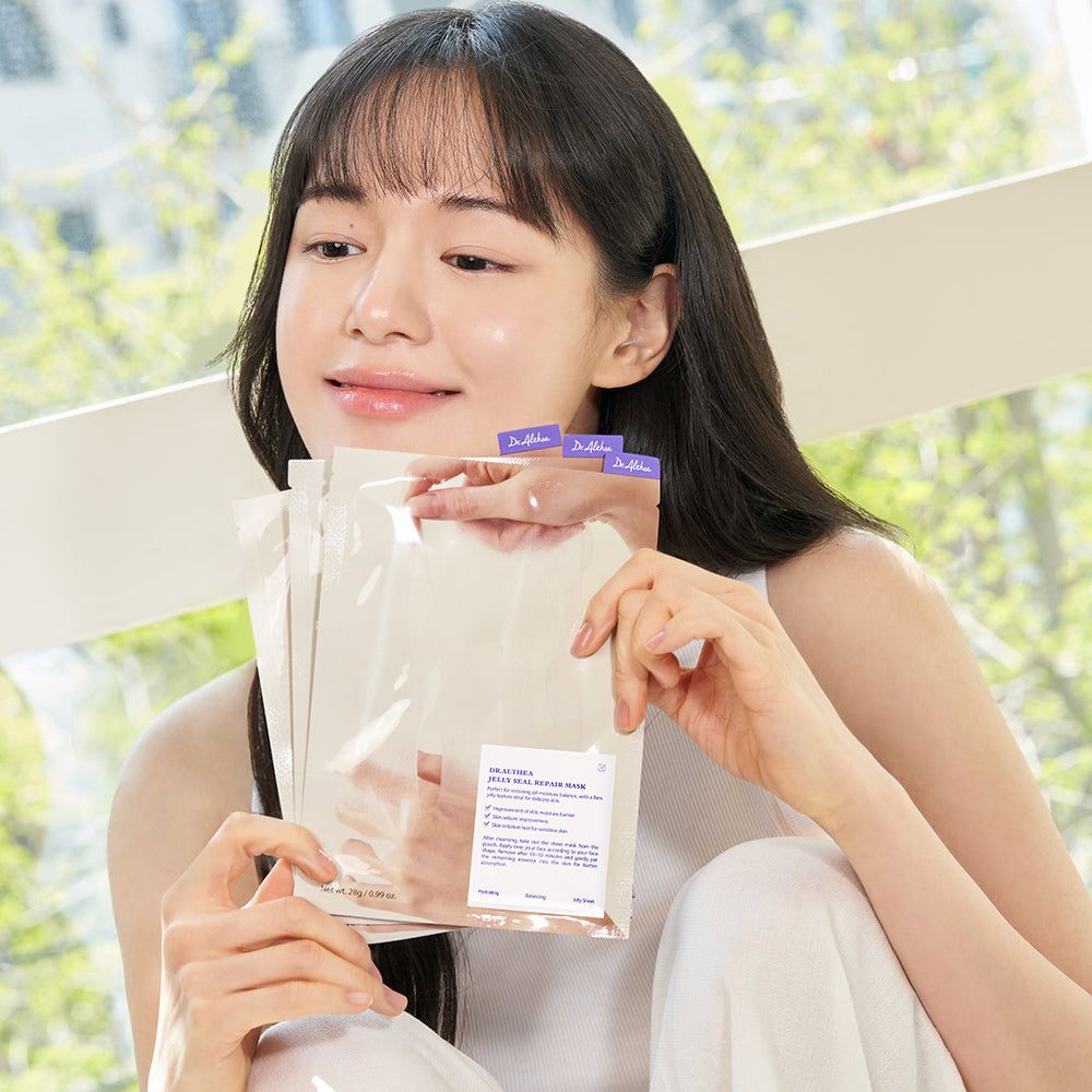 Een vrouw houdt meerdere verpakte sheetmaskers van het merk Dr. Althea vast.
