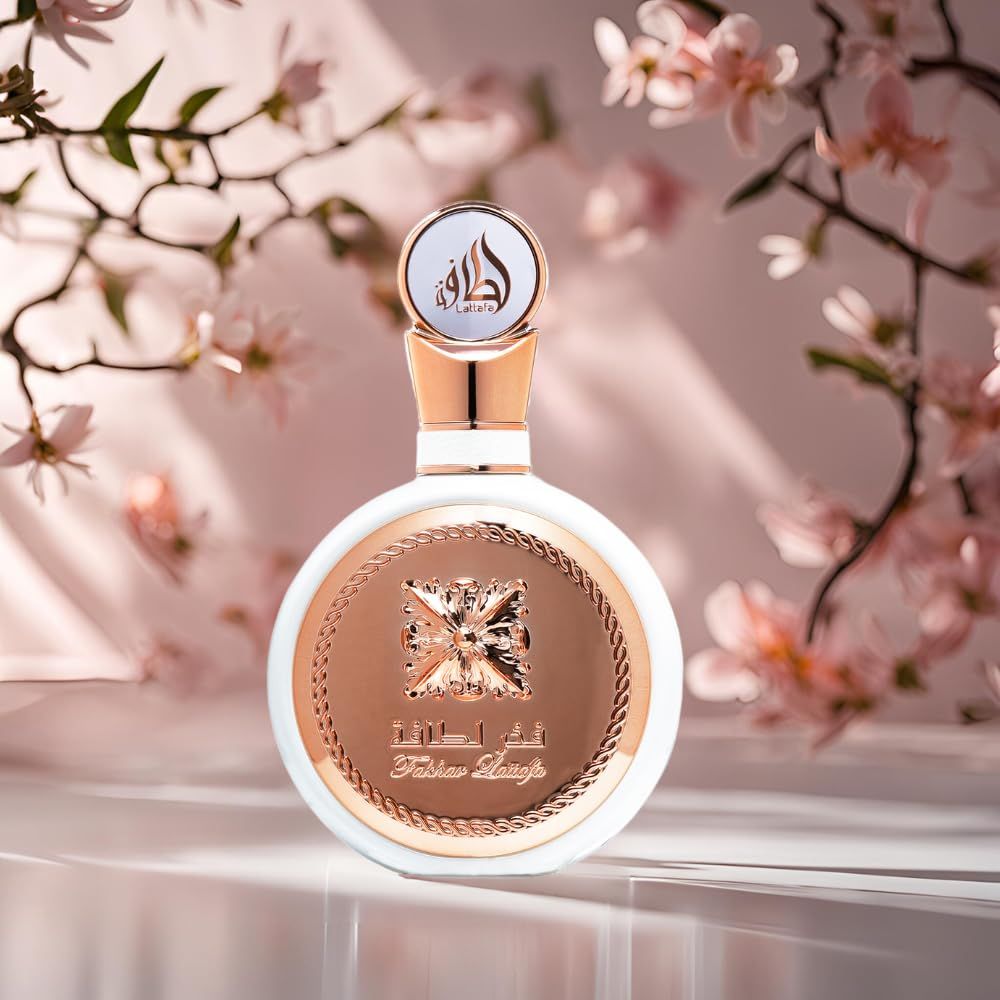Flacon de parfum blanc aux accents or rose, entouré de fleurs de cerisier roses.