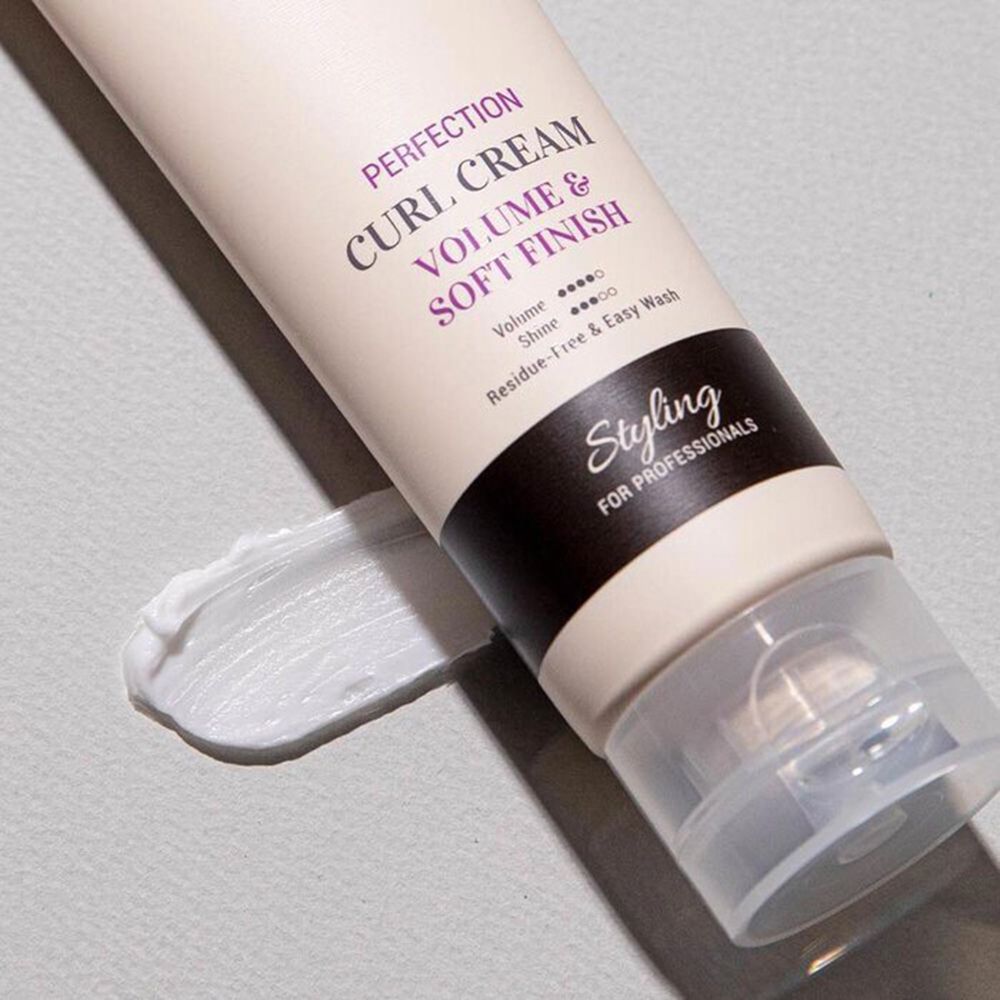 Close-up van een crèmetube en crème-uitstrijk. Tekst: CURLY SHYLL, Perfection Curl Cream, Volume & Soft Finish. Zwarte strook met tekst Styling.