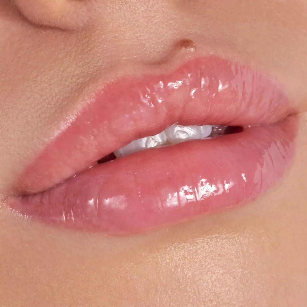 Close-up van lippen met glanzende lipgloss. De lippen zijn roze en glanzend.