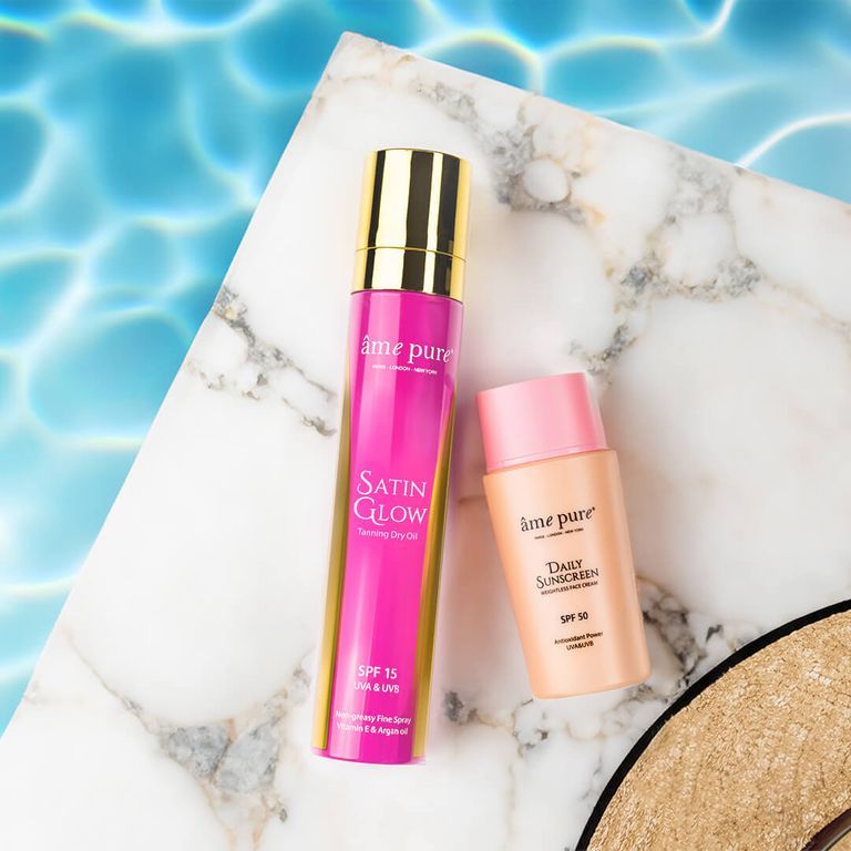 Âme Pure Daily Sunscreen SPF 50 et Satin Glow Tanning Dry Oil sur une dalle de marbre.