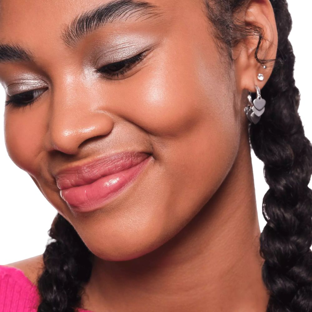 Gros plan d'une femme maquillée. Elle porte des boucles d'oreilles et a les cheveux tressés.
